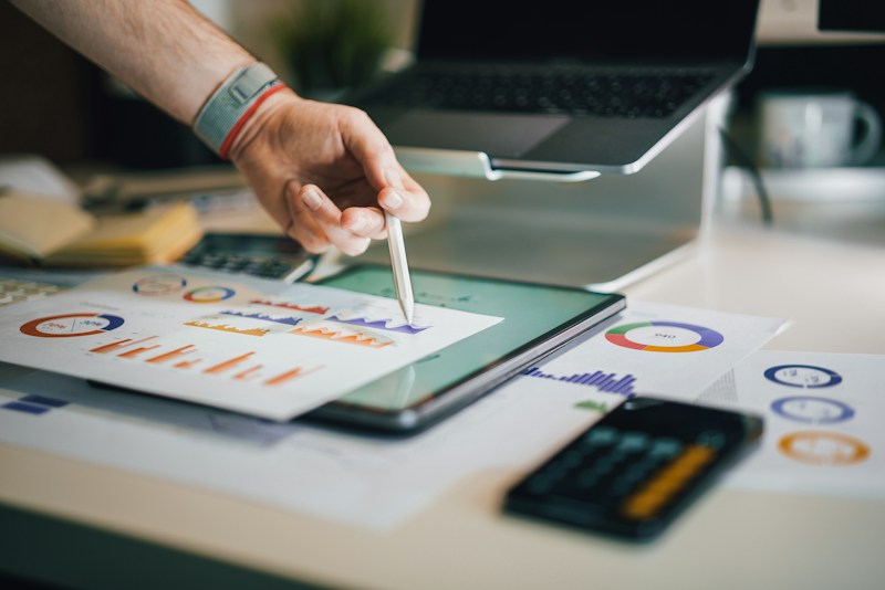 Financial charts, a tablet, and a calculator on a desk.